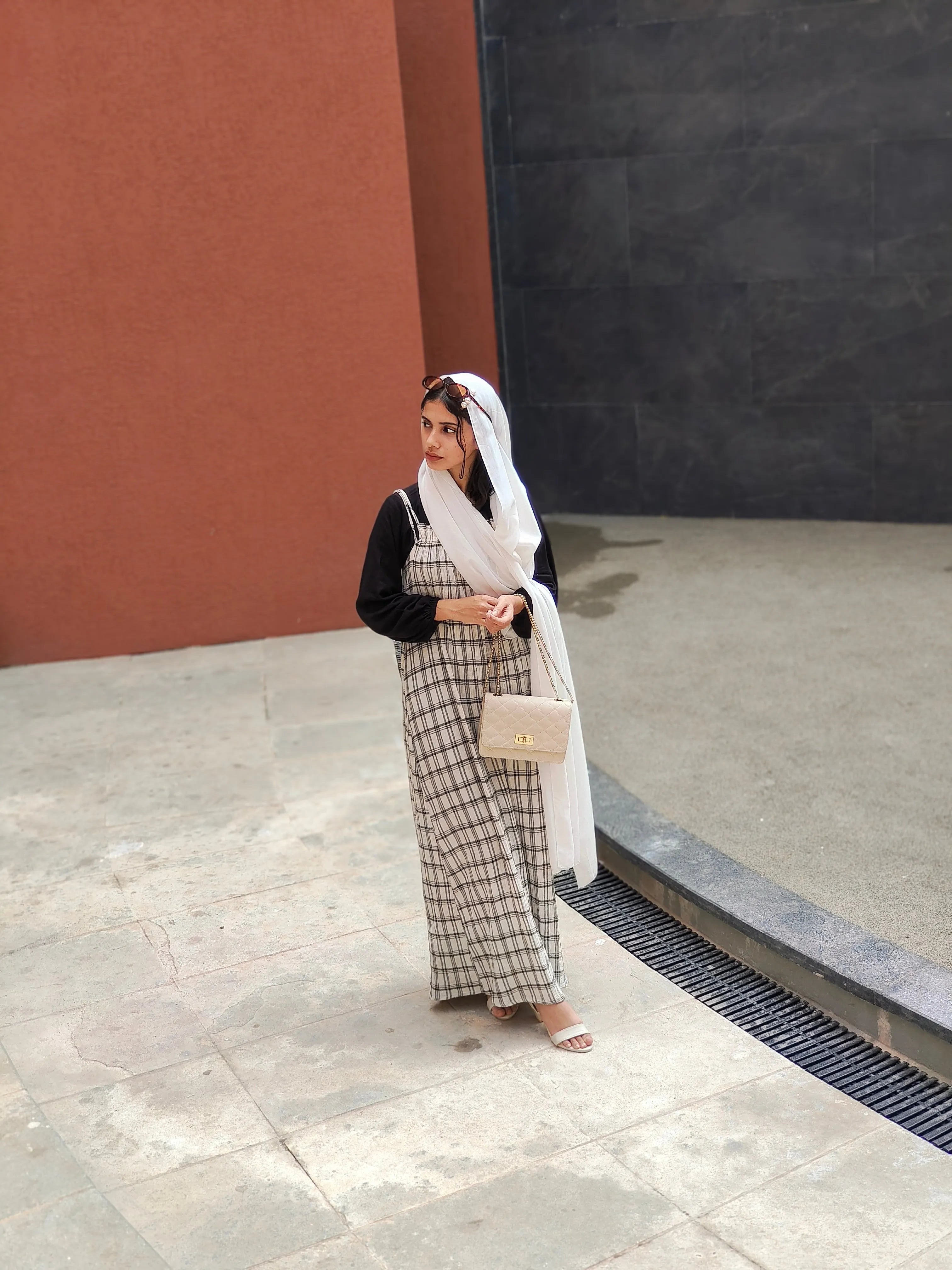 Yezwe modest dungaree dress in a plaid pattern worn with a stylish scarf and bag, perfect for casual outings