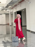 Elegant woman in reddish maroon top and skirt with stylish handbag and hijab in a modern indoor setting
