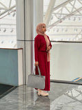 Stylish woman in a reddish maroon top and skirt, accessorized with a scarf and a checkered handbag