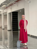 Model wearing a reddish maroon top and skirt with a matching headscarf in a modern indoor setting