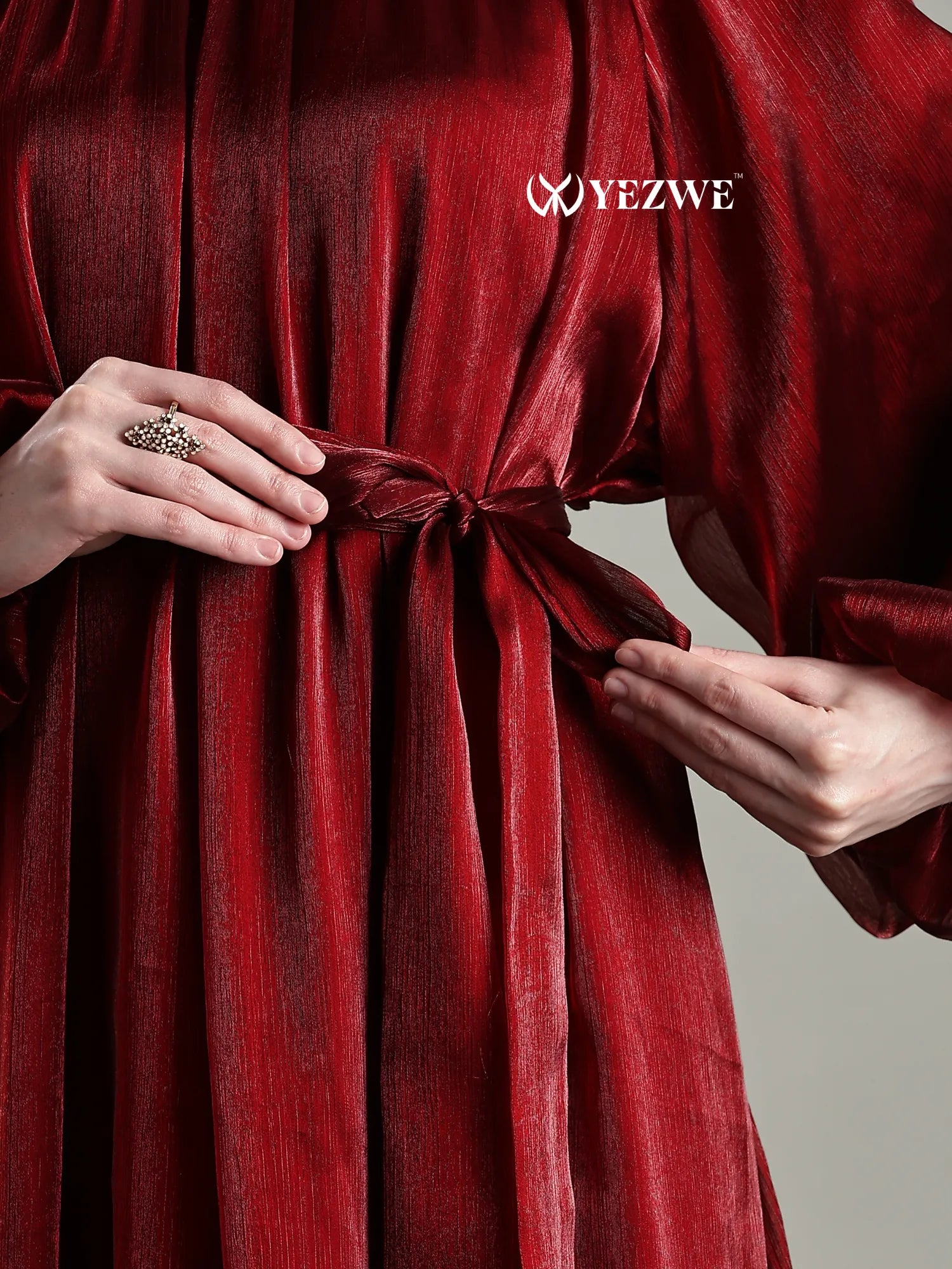 Close-up of Yezwe Full length jimicho Satin Flaired Maxi Dress in deep red with tied waist and textured fabric