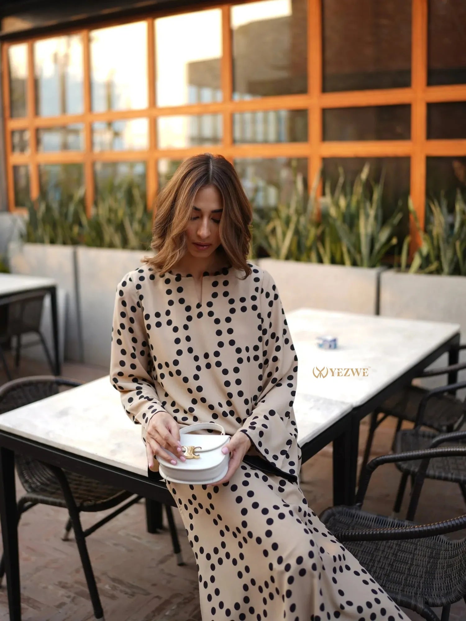 YEZWE beige co-ord set featuring a long tunic with pant in black polka dot pattern worn by woman sitting outdoors