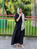 Woman wearing a modest black maxi dress by YEZWE with puff sleeves and a beige headscarf outdoors