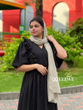 YEZWE modest black maxi dress with ruffle details and puff sleeves worn with a beige scarf outdoors