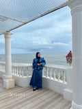 Woman wearing a blue modest co-ord set by YEZWE standing on a balcony overlooking the ocean