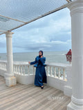 Woman wearing a blue modest co-ord set by YEZWE standing on a terrace overlooking the ocean