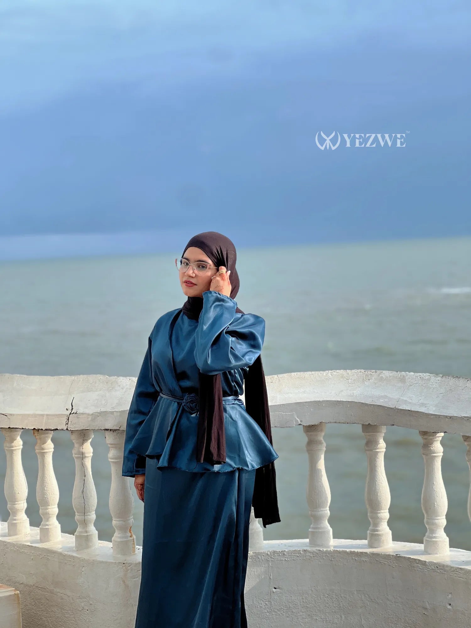 YEZWE modest co-ord set featuring a belted peplum top and long skirt in teal blue by the seaside