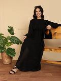 YEZWE Modest Maxi Dress black long sleeve pleated gown model seated on bench holding handbag