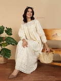 YEZWE Modest Maxi Dress cream eyelet cotton with puff sleeves seated model holding woven straw tote on bench