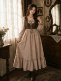 Woman wearing YEZWE vintage floral maxi dress with brown corset-style bodice, long puff sleeves, and tiered hem, styled in a warm vintage-inspired indoor setting.