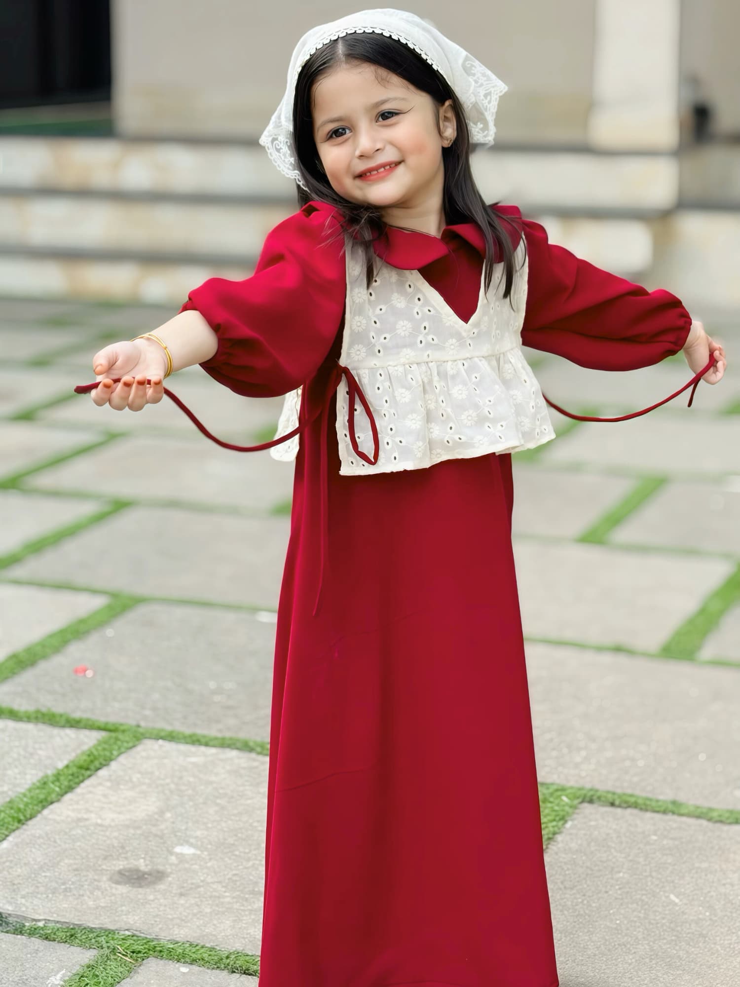 young girl wearing wine maroon modest maxi dress with a cream layered top playing and smiling outdoors in a candid pose