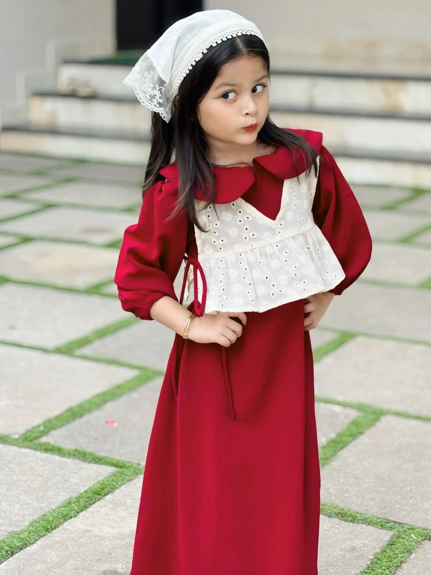 young girl wearing wine maroon modest maxi dress with a cream layered top posing playfully with hands on waist outdoors