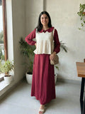 woman wearing wine maroon modest maxi dress with a cream layered sleeveless top standing indoors with a crossbody bag front view