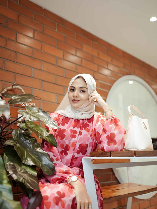 Woman wearing a floral pink dress and white hijab showcasing stylish outfit with style ideas