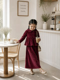 Junior girl wearing maroon velvet long sleeve co-ord set holding coffee cup in cafe setting