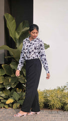 Stylish women wearing black bell button pants women paired with a floral blouse in an outdoor setting