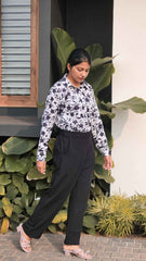 Woman wearing black bell button pants women styled with a floral print top in a lush outdoor setting