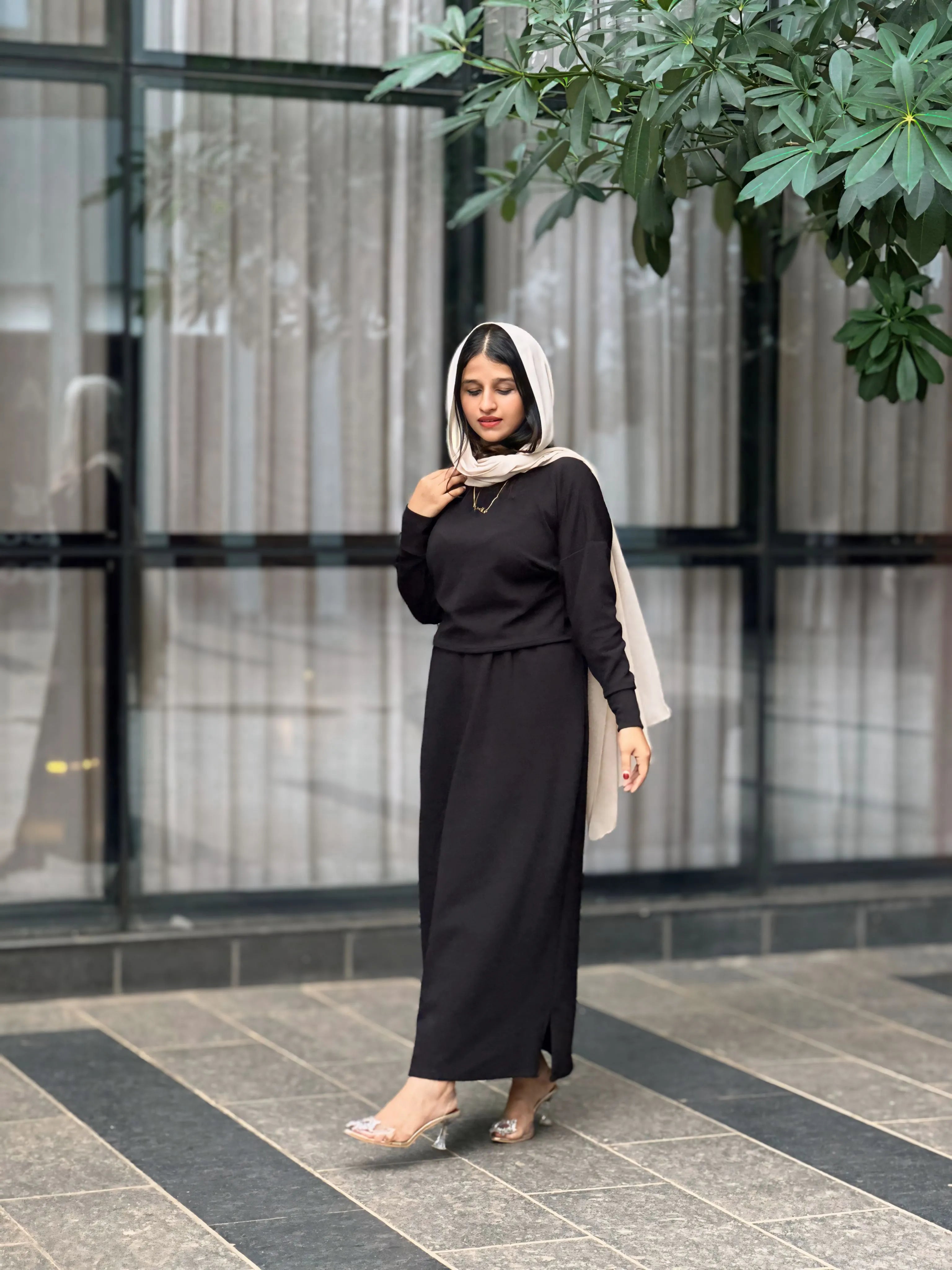Elegant model wearing a black Turkish top and skirt with a stylish headscarf and subtle accessories