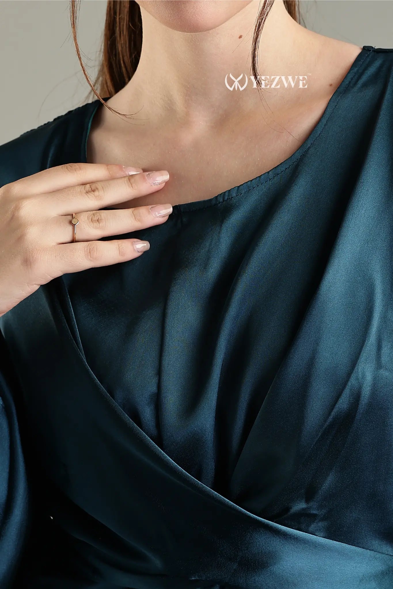 Close-up of a woman's hand on a blue satin flare modest gown by YEZWE showcasing luxurious fabric