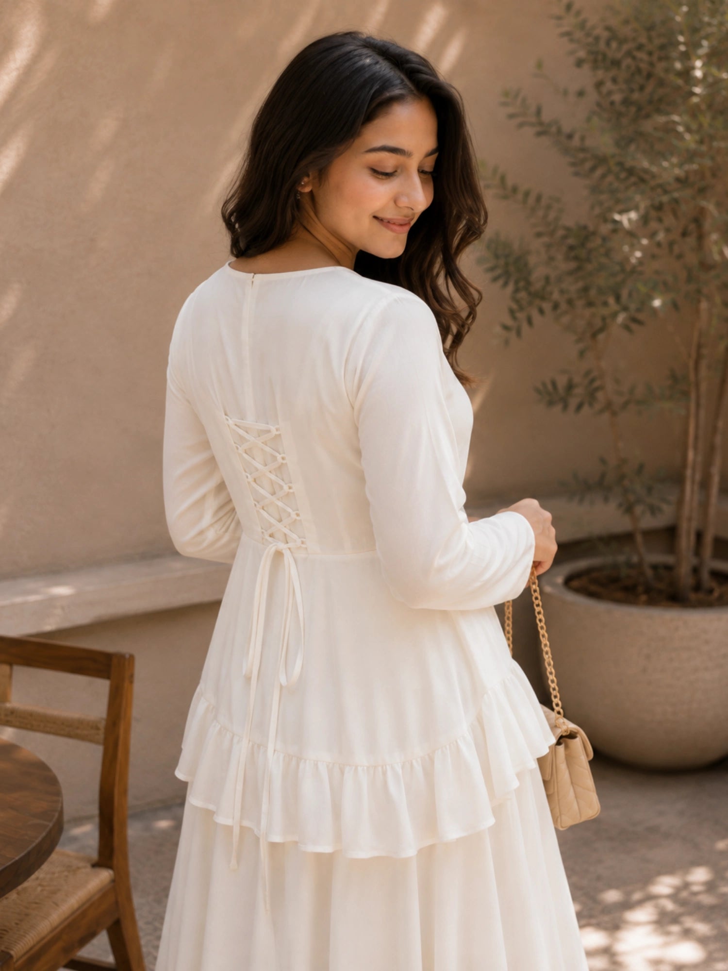 Back view of the Ivory Faux Georgette Asymmetric Ruffle Maxi Dress featuring a lace-up design and tiered ruffles.