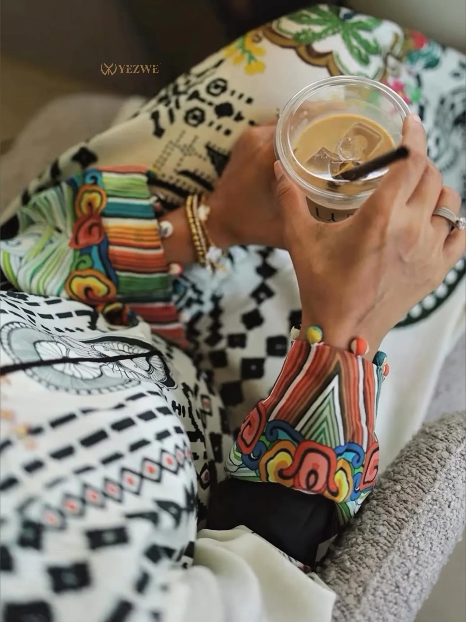 Stylish YEZWE Jalabiya Maxi Dress with colorful patterned sleeves and a refreshing iced coffee