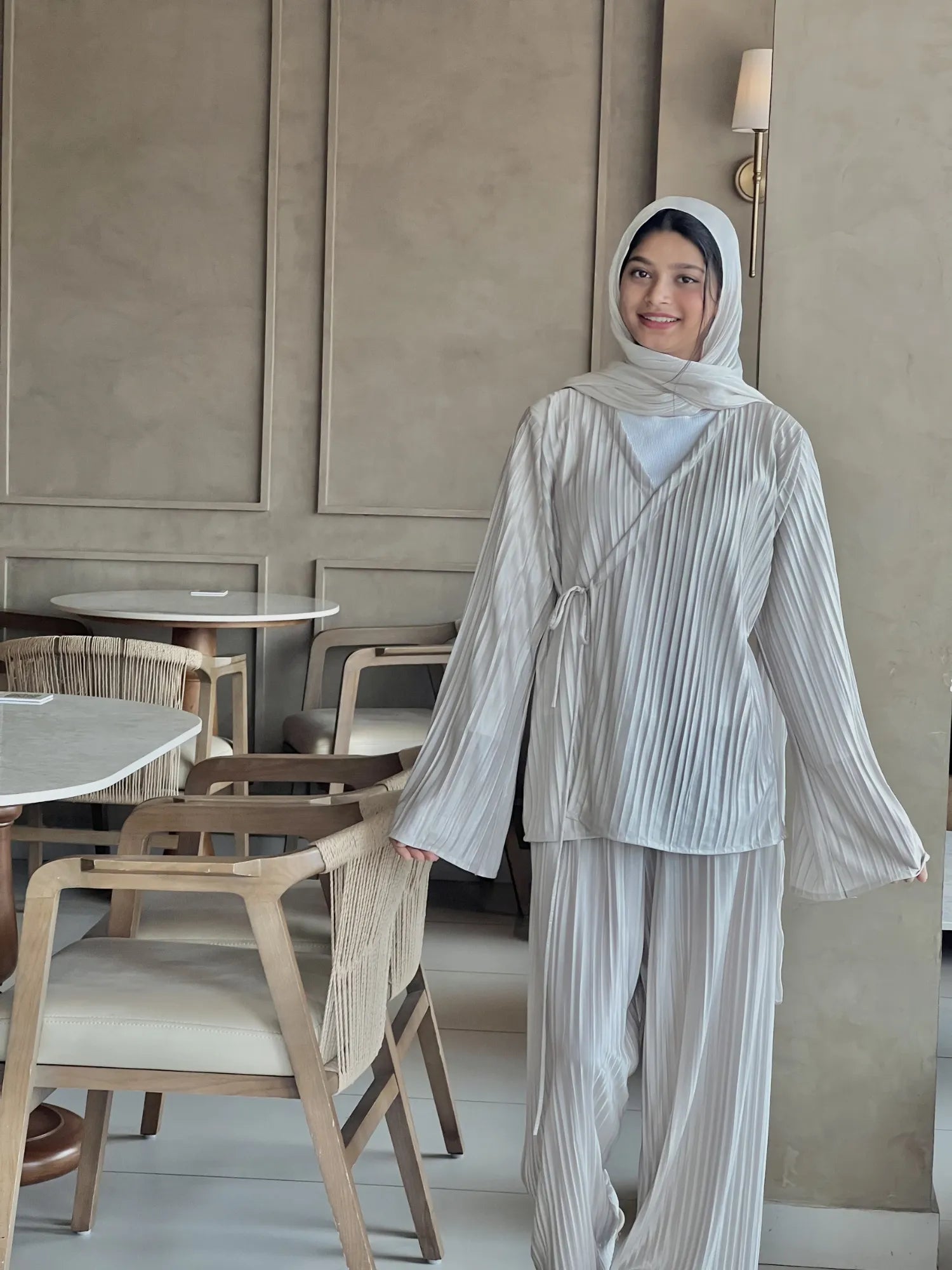 Front view of beige Korean pleated co-ord set for women with modest fit, featuring a flowy pleated top, wide sleeves, matching pants, and hijab styling