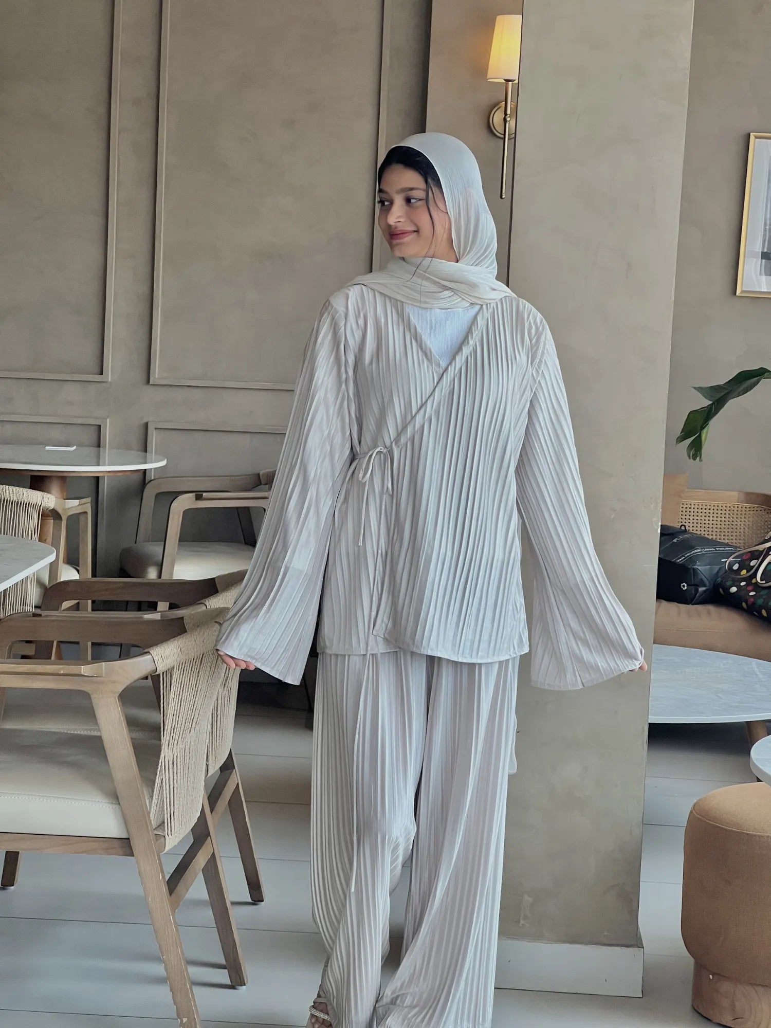 Side view of beige Korean pleated co-ord set for women with modest fit, featuring a flowy pleated top, wide sleeves, matching pants, and hijab styling