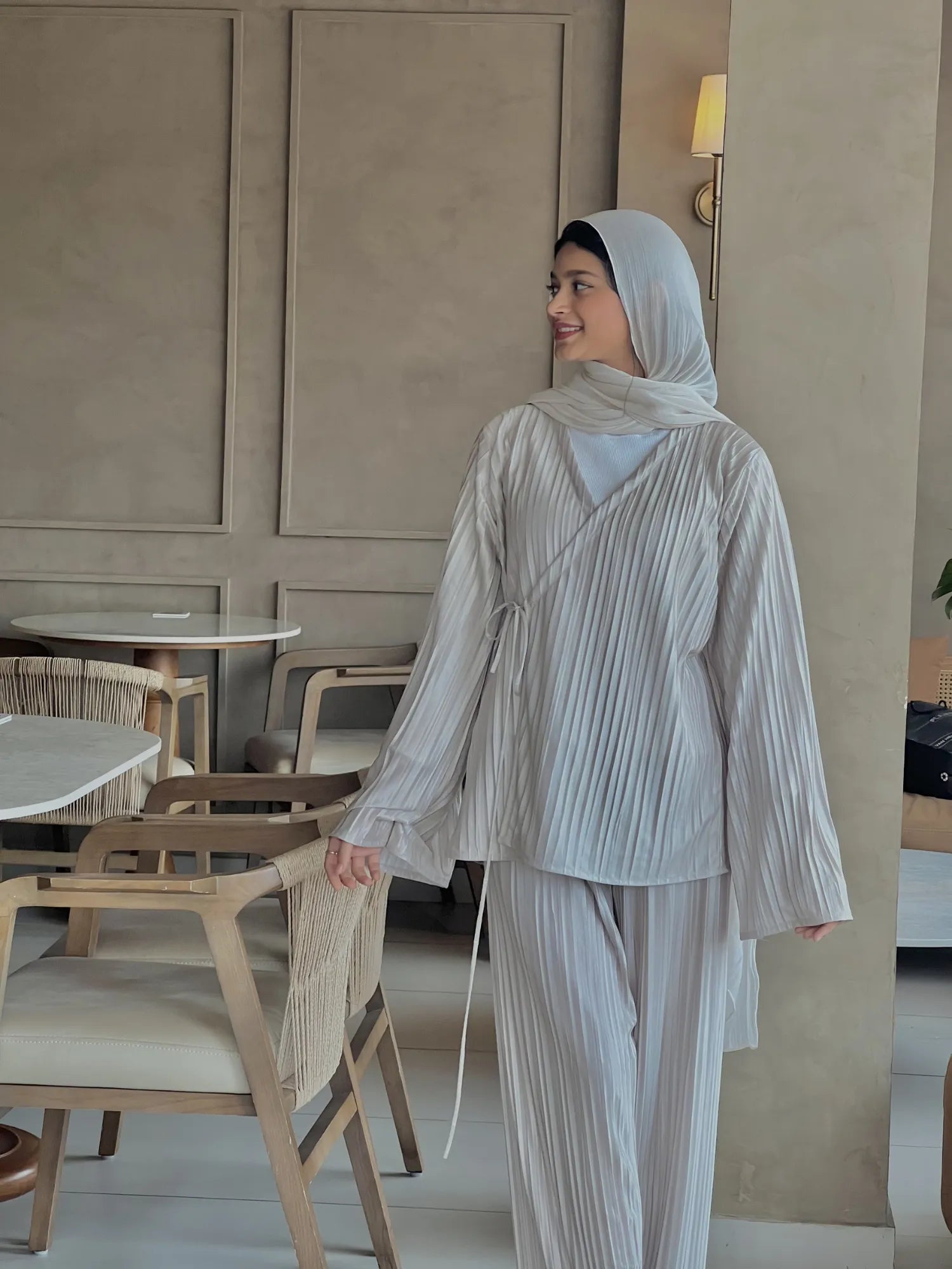 Walking pose of beige Korean pleated co-ord set for women with modest fit, featuring a flowy pleated top, wide sleeves, matching pants, and hijab styling