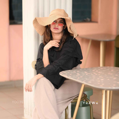 Chic woman wearing a modest black co-ord set with stylish accessories, seated at a café table