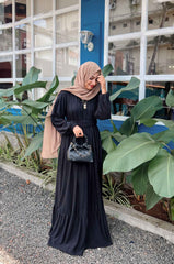 Yezwe modest black maxi dress with long sleeves and tiered skirt, styled with a hijab and handbag