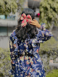 Back view of a woman wearing a modest floral georgette maxi dress with a bow in her hair