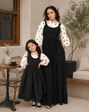 Mom & Daughter Black Pinafore Dress Set with Embroidered Kora Cotton Inner in a stylish outdoor setting