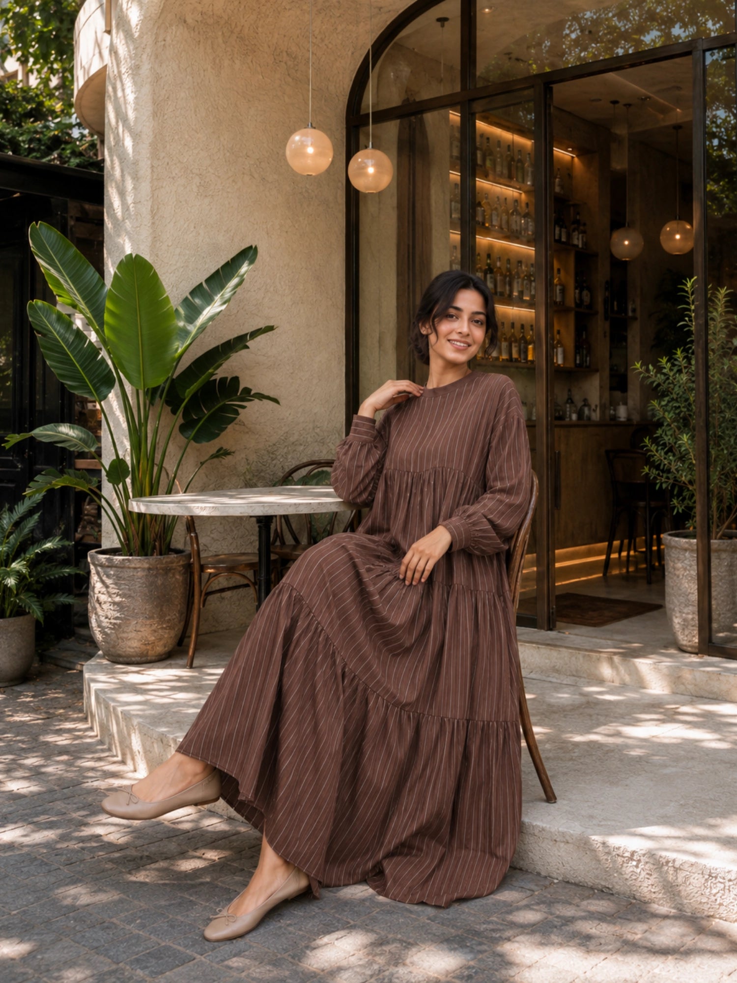 Oversized Striped Tiered Maxi Dress for Women | Loose Flared Modest Dress in Brown worn by a woman in a chic cafe setting