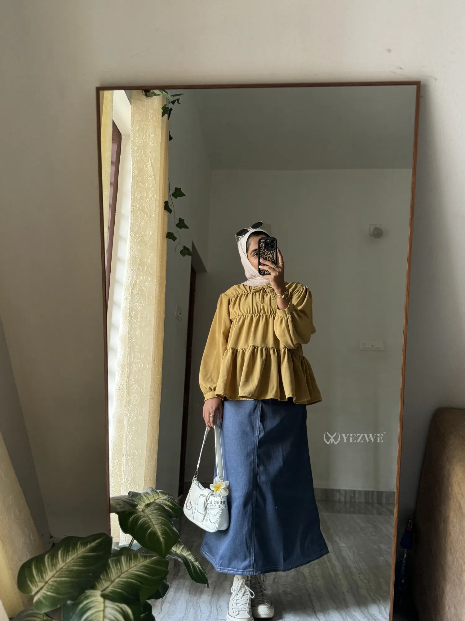 Stylish woman in a Peplum Top with Denim Skirt posing in front of a mirror for a chic look