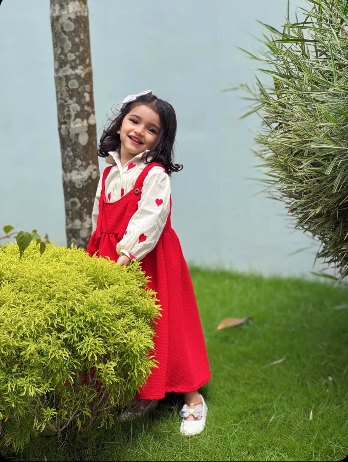 Happy young girl wearing a red Pinafore For Junior Girls with a white blouse outdoors