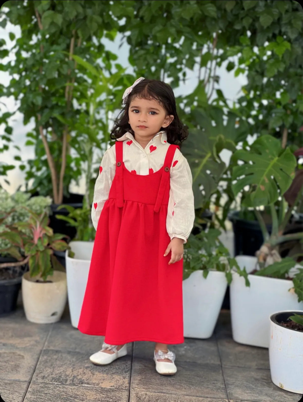 Red pinafore for junior girls worn over white blouse with heart prints by YEZWE