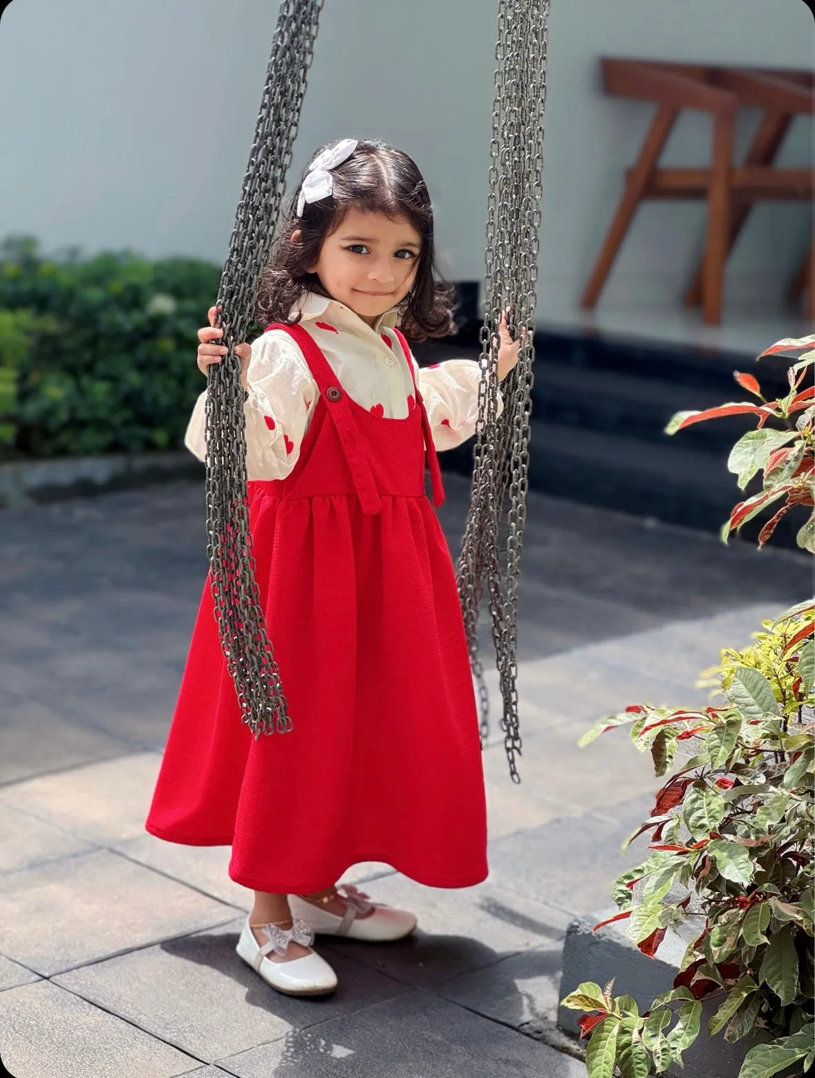 Pinafore For Junior Girls red sleeveless dress worn by young girl on a swing outdoors
