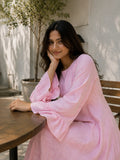 Model wearing a pink striped maxi dress, posing at a cafe with a relaxed vibe