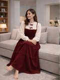 Woman sitting on a couch wearing a red velvet vintage maxi dress with a white blouse