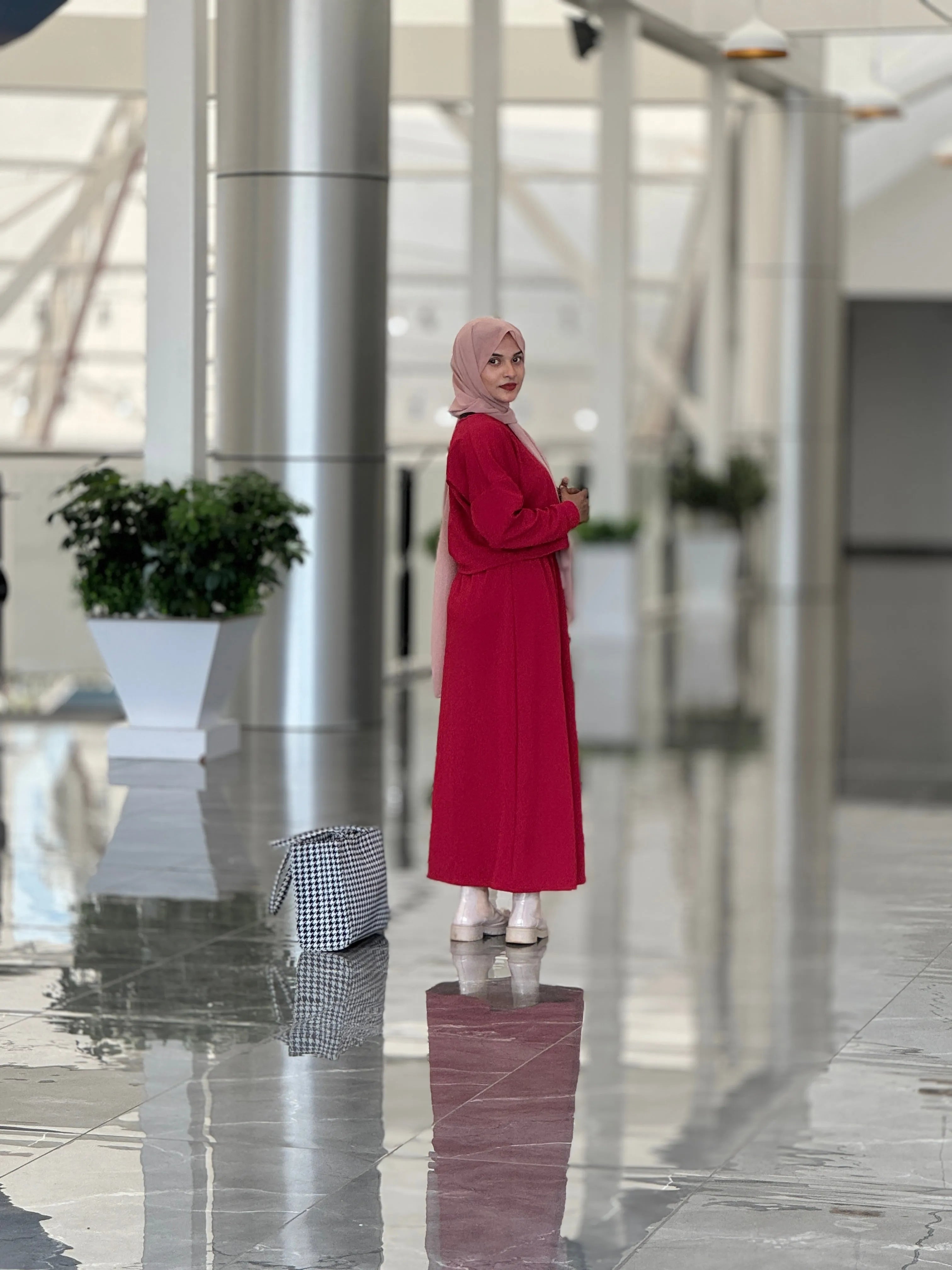 Stylish woman in a reddish maroon top and skirt posing elegantly in a modern indoor setting