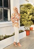 Model wearing a yellow print top and white pants with a stylish headscarf and heels