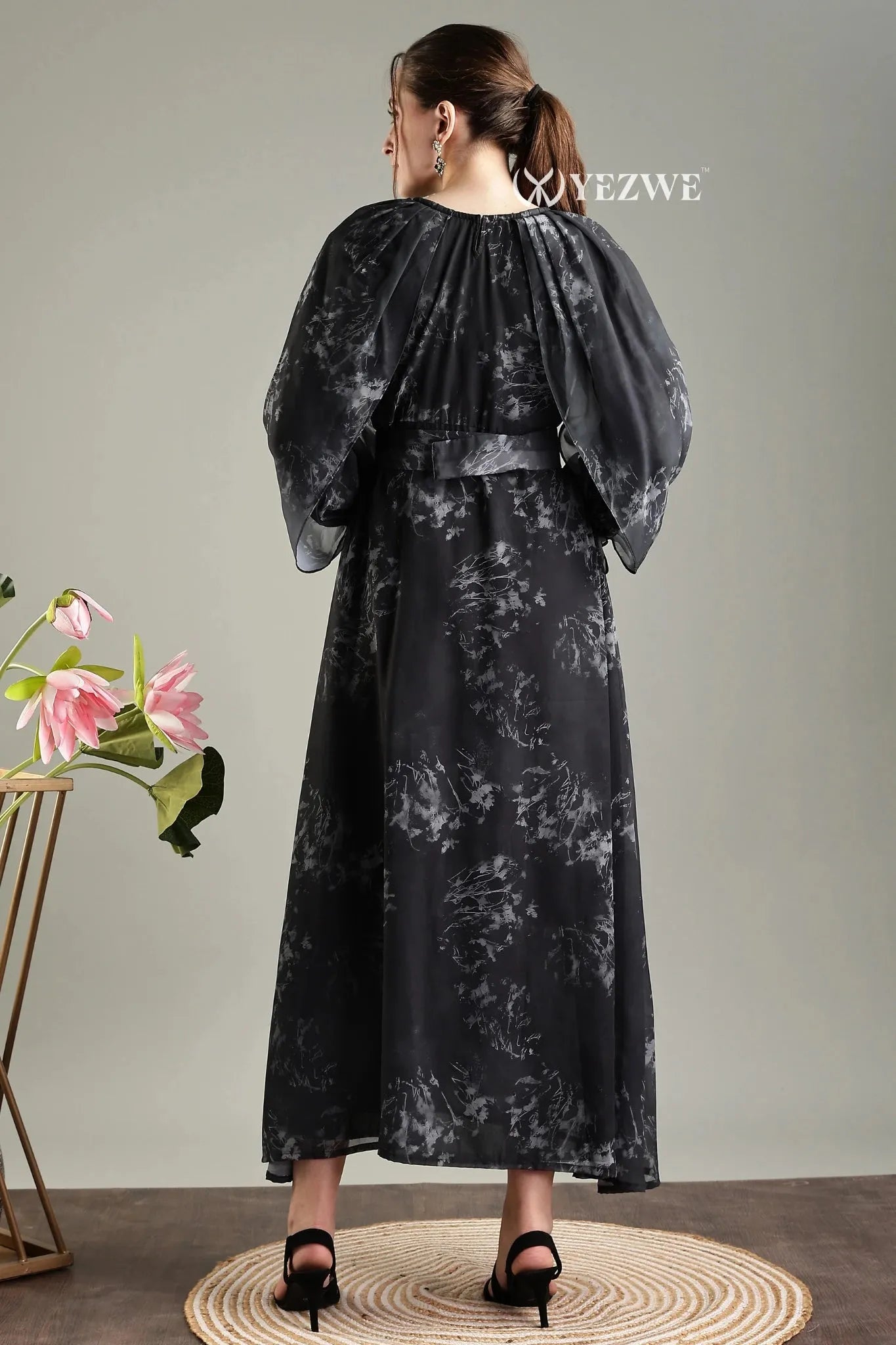 Back view of black floral print belted modest maxi dress by YEZWE with flowing sleeves