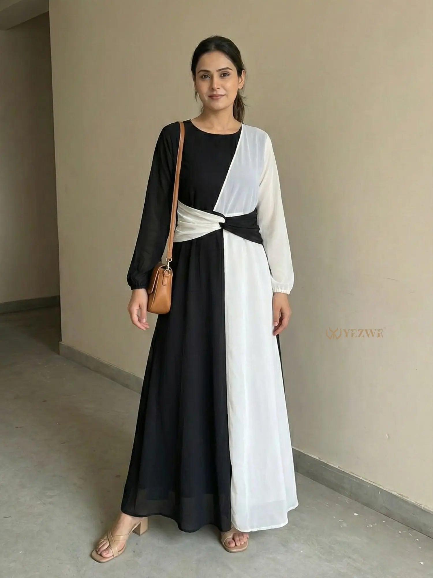 young woman wearing a black and white dual tone modest maxi dress standing indoors full length front view