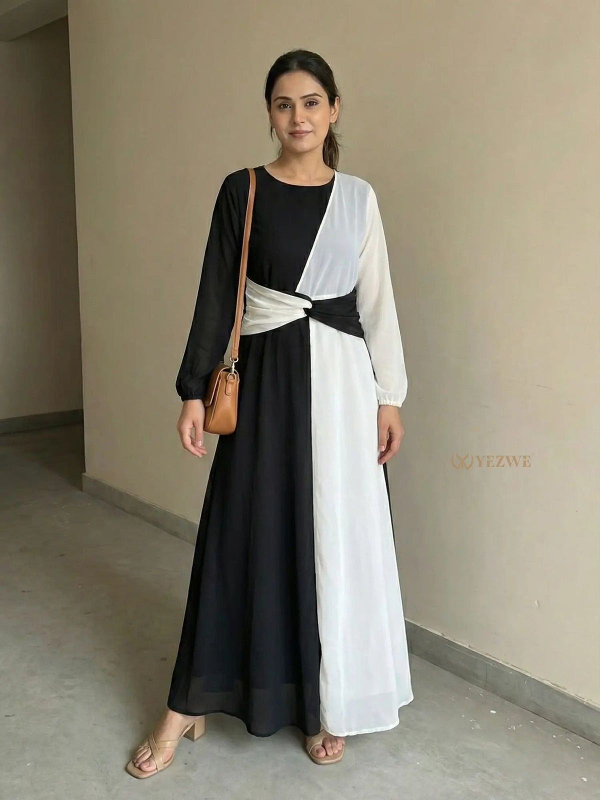 young woman wearing a black and white dual tone modest maxi dress standing indoors full length front view