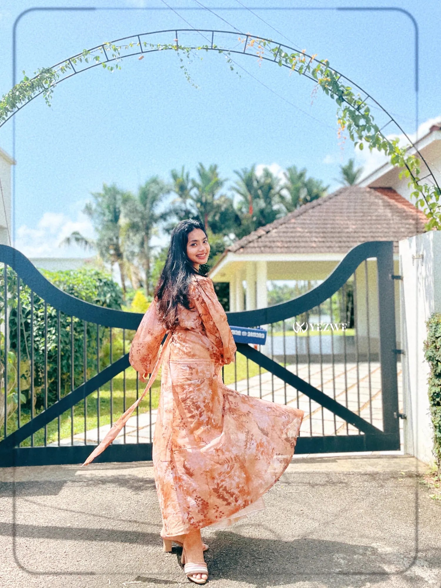 Stylish brown floral georgette maxi dress flowing in the breeze with a beautiful outdoor backdrop
