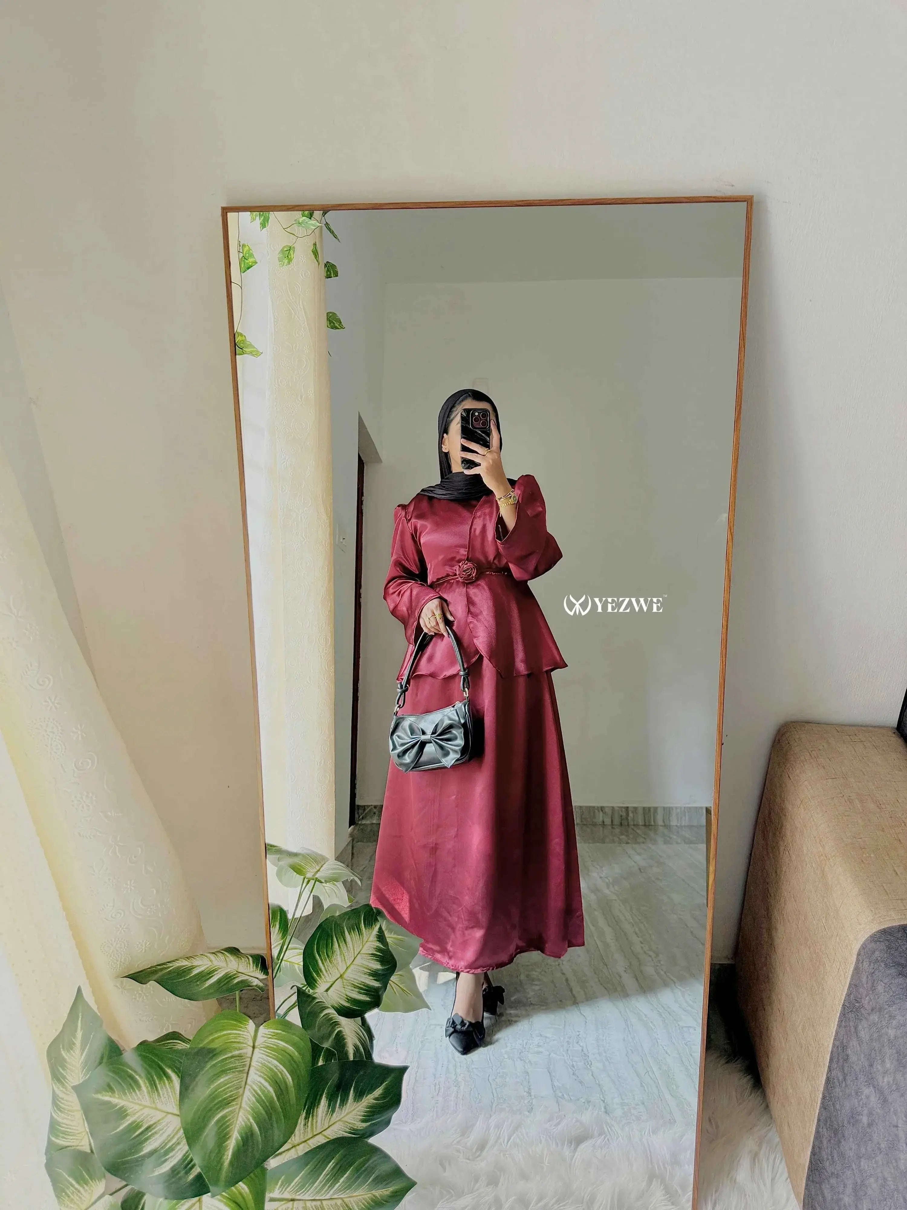 Chic burgundy satin co-ord set styled with a black handbag in a modern interior