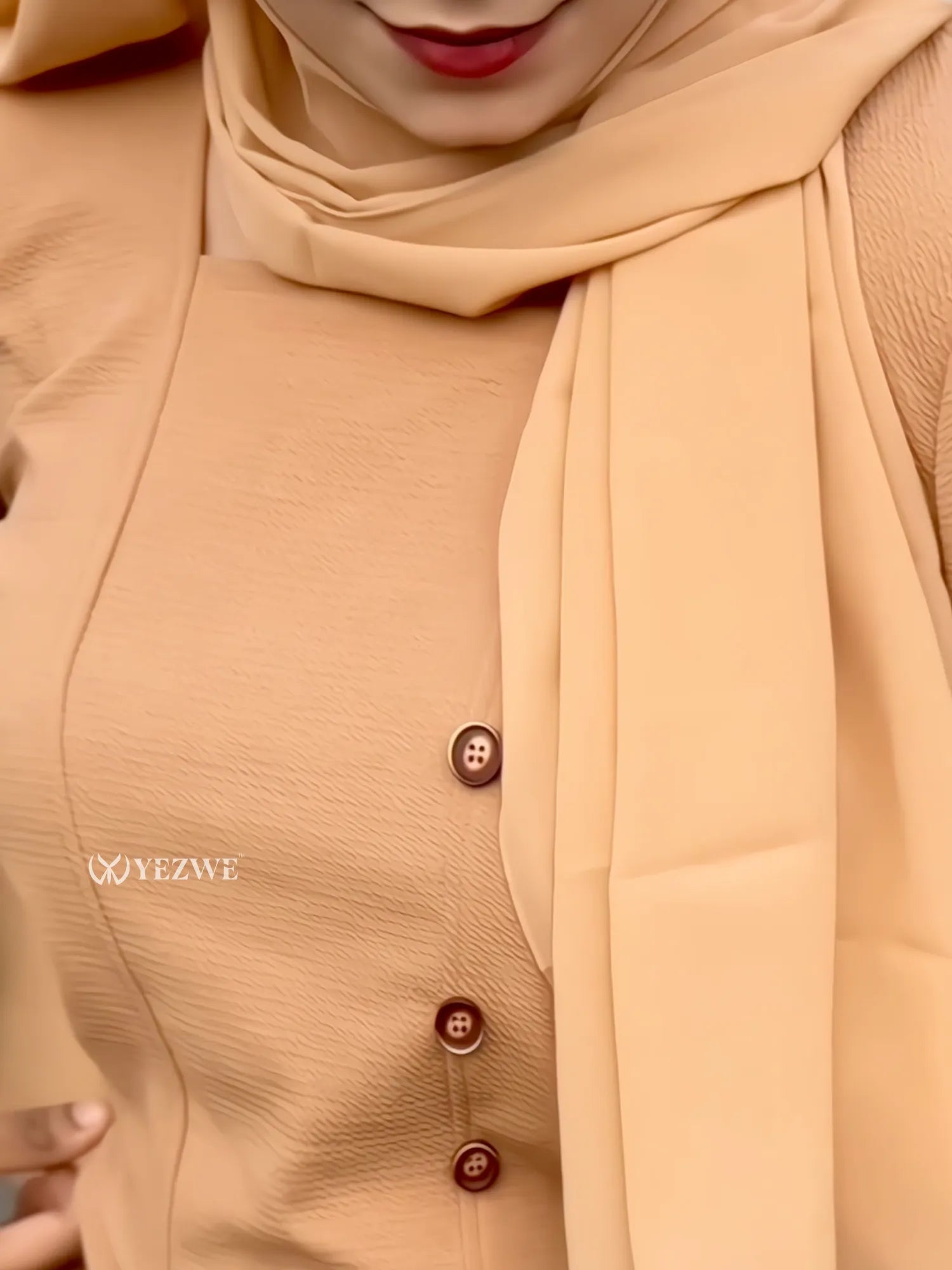 Close-up of a model wearing a camel brown modest co-ord set with decorative buttons and matching scarf