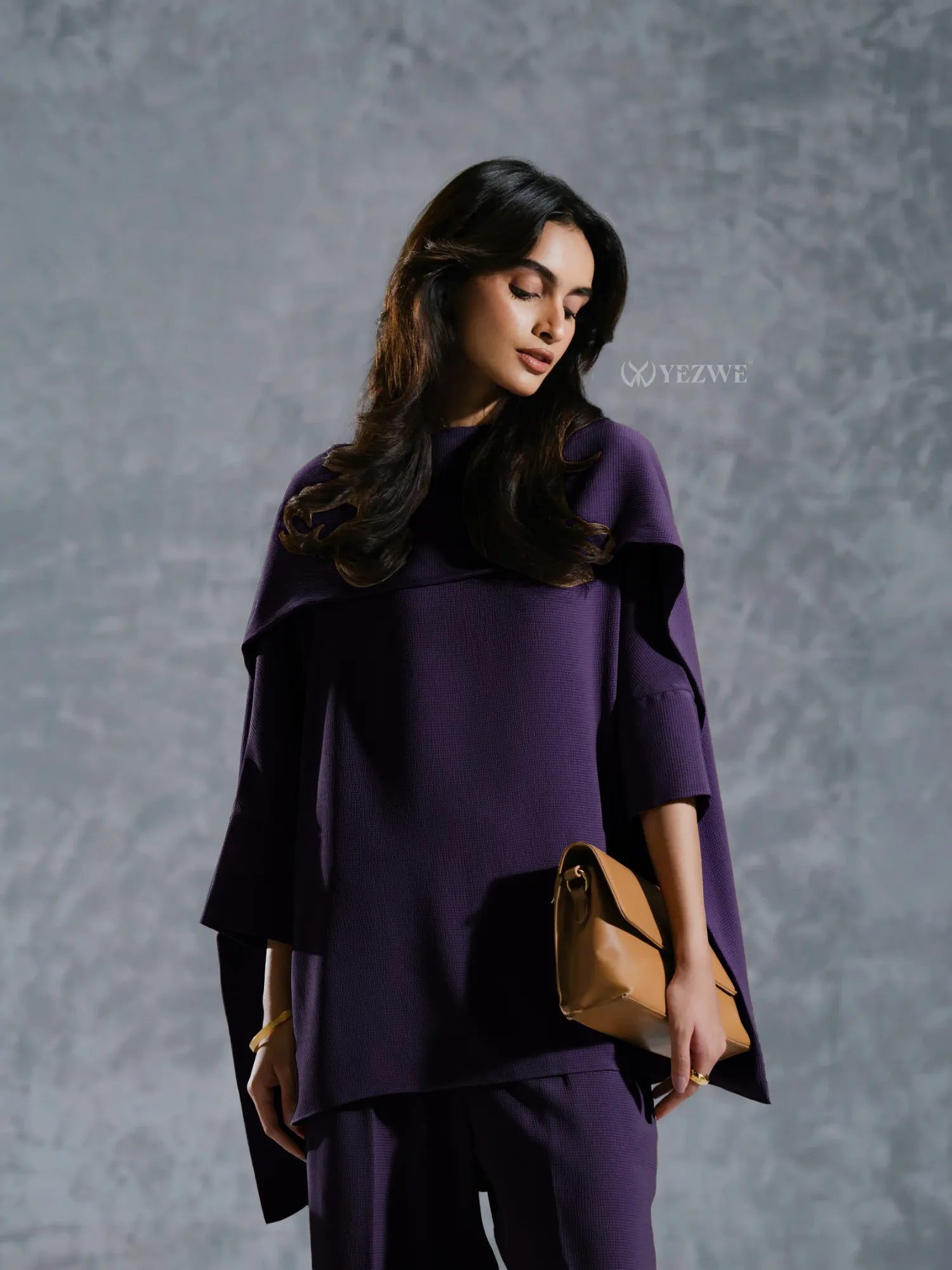 Woman wearing a stylish purple Co-Ord Set from YEZWE holding a tan clutch bag