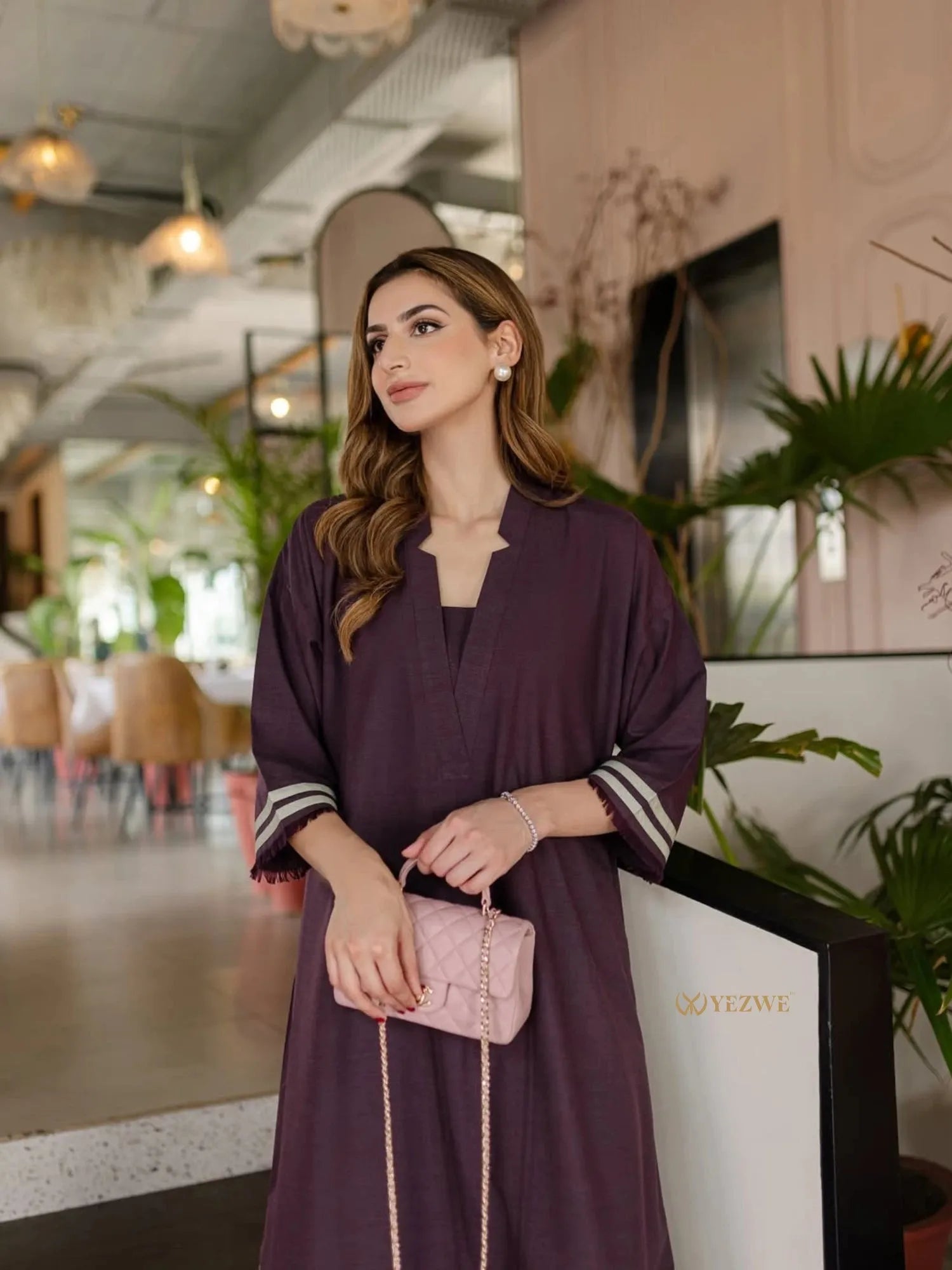 Woman wearing a stylish dark purple YEZWE Co-Ord Set holding a pink quilted handbag indoors