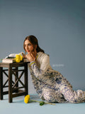 Woman wearing YEZWE blue and white floral Co-Ord Set sitting on floor against gray background